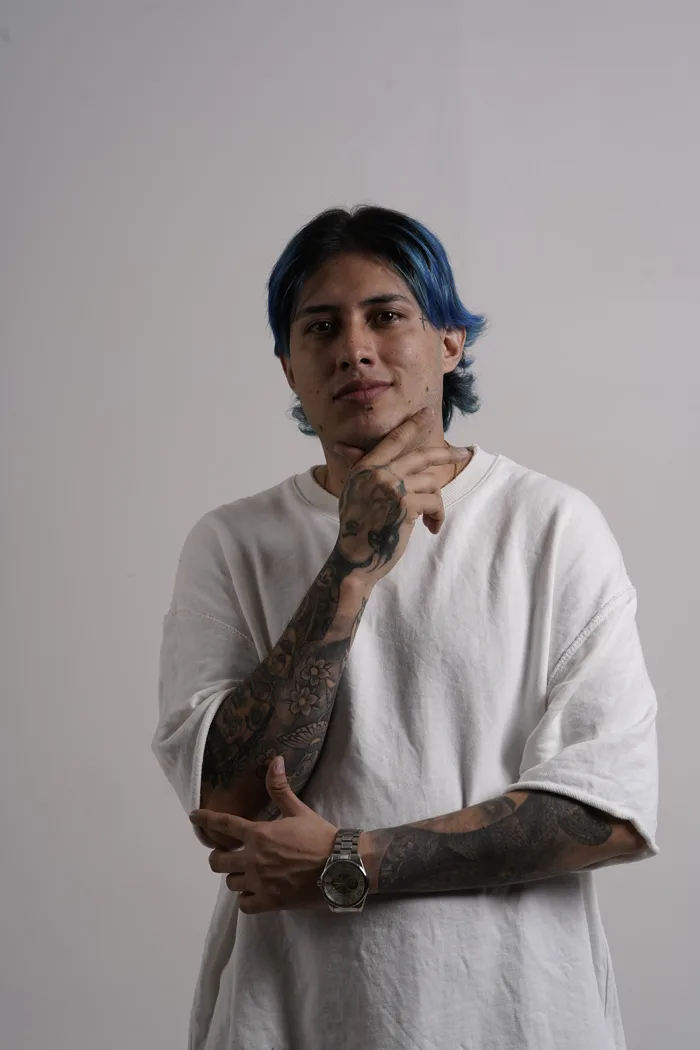 SEVEN77 à mi-corps, bras croisés, des tatouages de fleurs le long de l'avant-bras