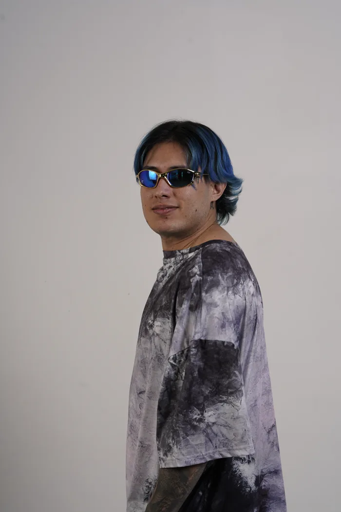 SEVEN77 de profil en tee-shirt tie-dye gris et lunettes miroir bleues